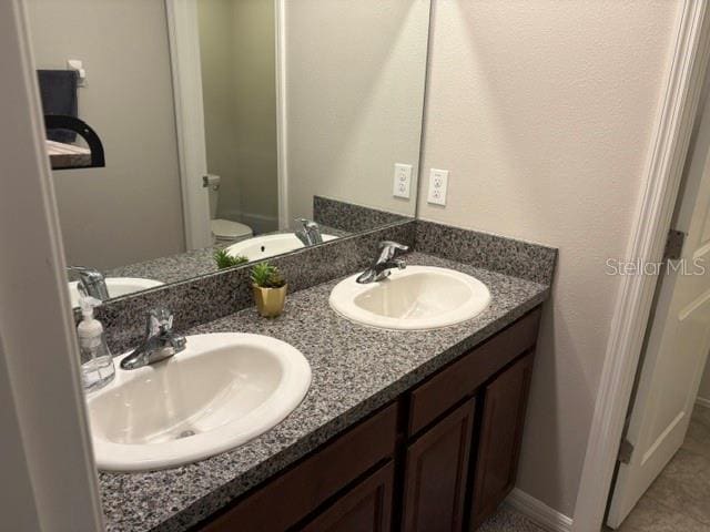 full bathroom featuring a sink, double vanity, and toilet