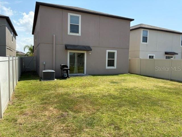 rear view of house featuring a lawn, stucco siding, and a fenced backyard