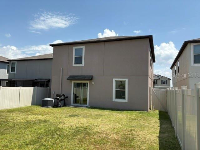 back of house featuring a fenced backyard, stucco siding, and a lawn