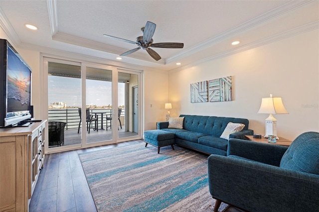 living area featuring a tray ceiling, wood-type flooring, ceiling fan, crown molding, and recessed lighting