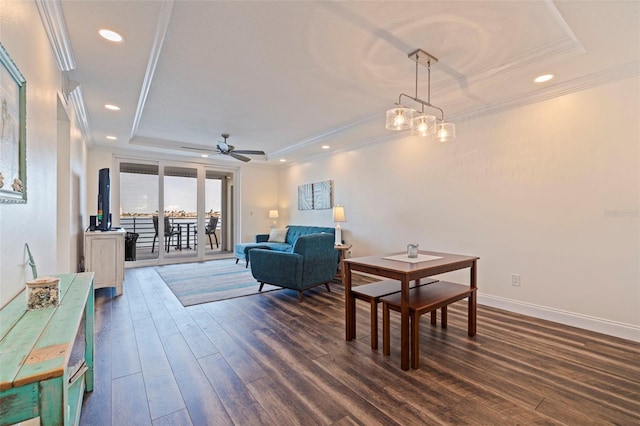 living room with a tray ceiling, dark wood-style flooring, crown molding, recessed lighting, and a ceiling fan