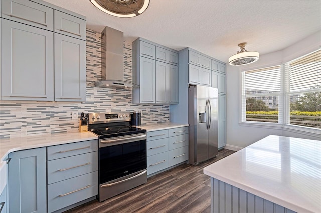 kitchen with wall chimney exhaust hood, stainless steel appliances, gray cabinets, dark wood finished floors, and a textured ceiling