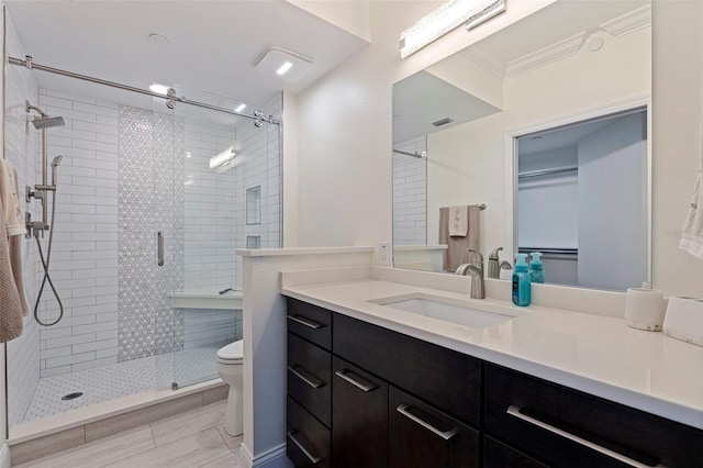bathroom featuring a shower stall, toilet, vanity, and ornamental molding