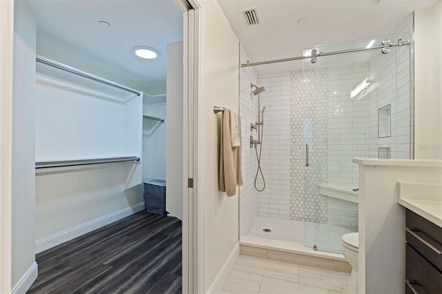 bathroom featuring a stall shower, vanity, toilet, and baseboards