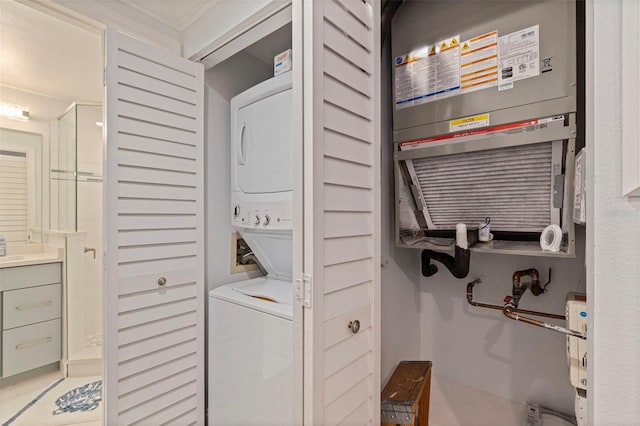 clothes washing area featuring stacked washer / drying machine and ornamental molding