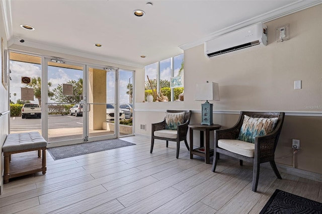 sitting room featuring a wall unit AC, light wood finished floors, and ornamental molding