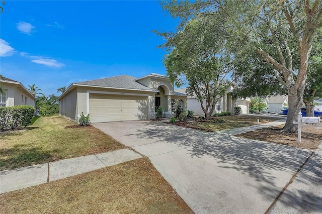 view of front of home featuring an attached garage, stucco siding, driveway, and a front yard
