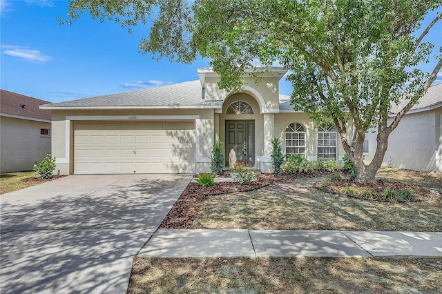 view of front of house with stucco siding, a garage, and driveway