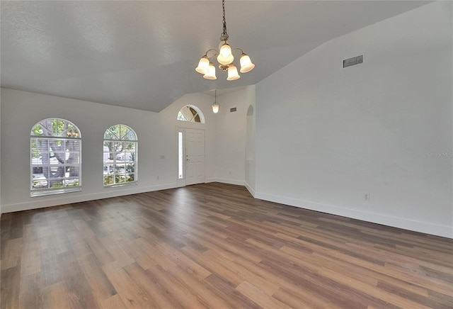 spare room with lofted ceiling, a chandelier, wood finished floors, and baseboards