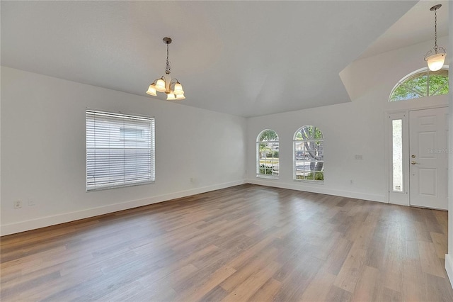 foyer entrance featuring a chandelier, baseboards, wood finished floors, and vaulted ceiling