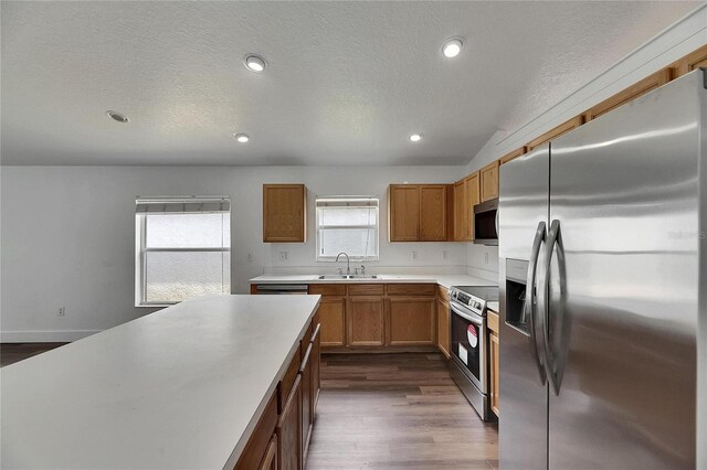 kitchen featuring stainless steel appliances, a sink, dark wood-type flooring, light countertops, and a textured ceiling