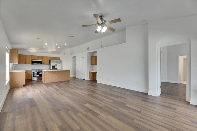 unfurnished living room featuring a ceiling fan, recessed lighting, wood finished floors, arched walkways, and baseboards