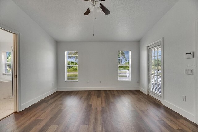 spare room with dark wood-style floors, a ceiling fan, a textured ceiling, and baseboards