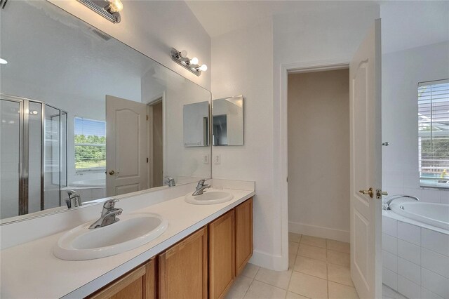 bathroom featuring healthy amount of natural light, tile patterned flooring, double vanity, and a shower stall