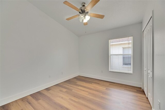 unfurnished bedroom with light wood-style flooring, baseboards, and lofted ceiling