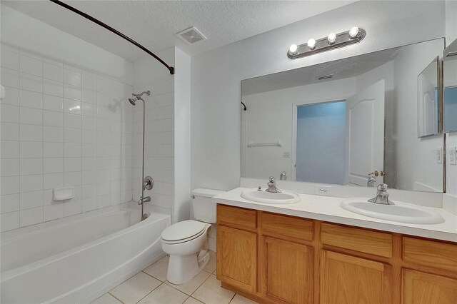 full bath with tile patterned floors, toilet, shower / tub combination, double vanity, and a textured ceiling
