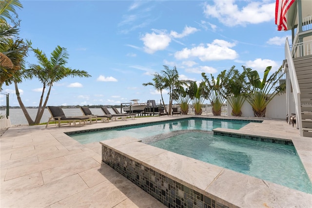 view of swimming pool with a pool with connected hot tub, a patio, and fence