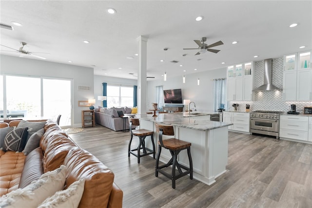 kitchen featuring open floor plan, appliances with stainless steel finishes, wall chimney range hood, ceiling fan, and recessed lighting