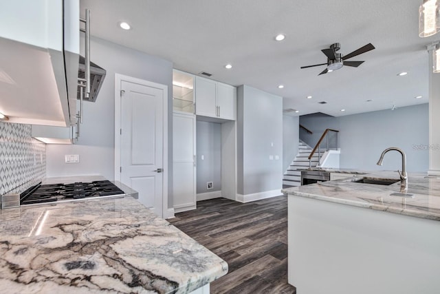 kitchen featuring a sink, light stone countertops, dark wood finished floors, ceiling fan, and white cabinetry