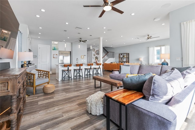 living area with a ceiling fan, stairway, recessed lighting, and wood finished floors