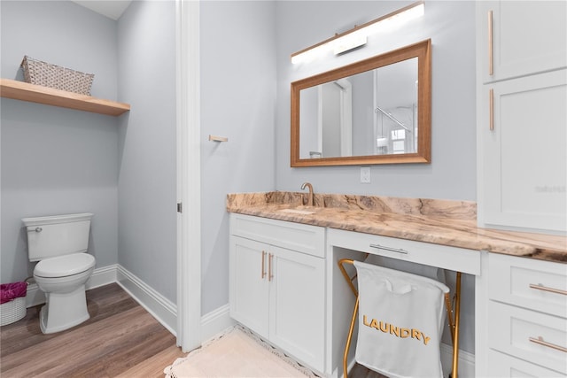 bathroom featuring toilet, wood finished floors, vanity, and baseboards
