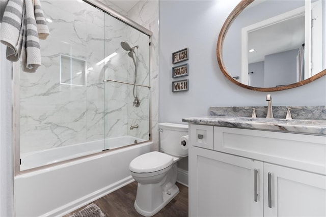 bathroom featuring wood finished floors, toilet, vanity, and shower / bath combination with glass door