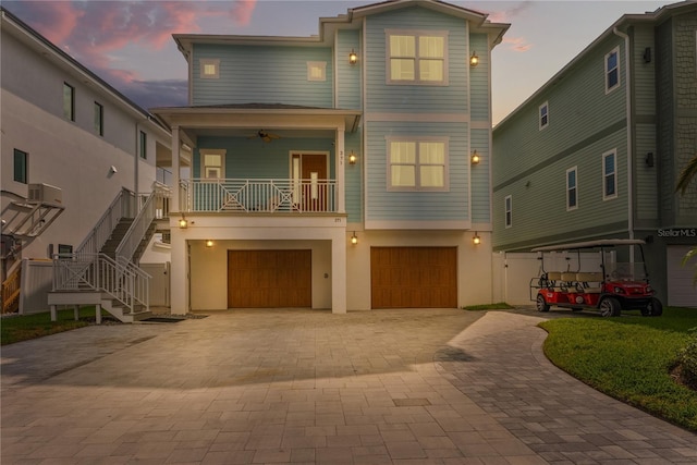 view of front of home with a garage, stairway, decorative driveway, a ceiling fan, and a porch