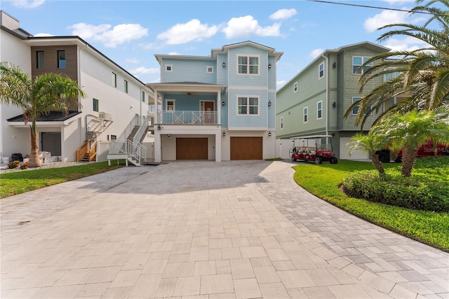 raised beach house featuring stairs, a garage, decorative driveway, ceiling fan, and stucco siding