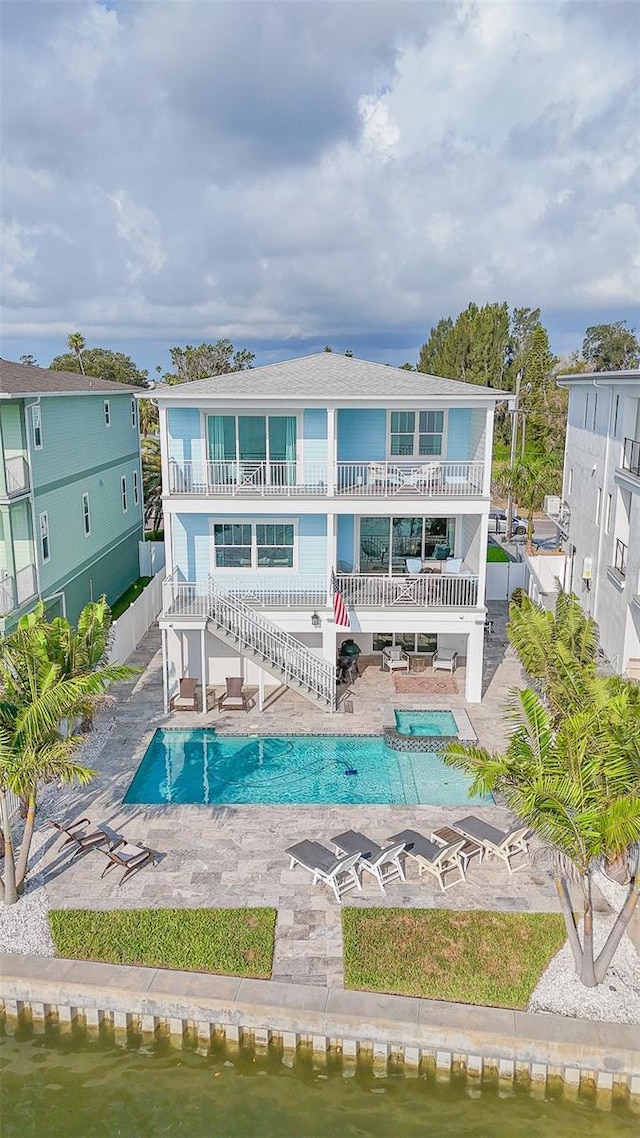 back of property featuring a balcony, a fenced backyard, and an outdoor pool