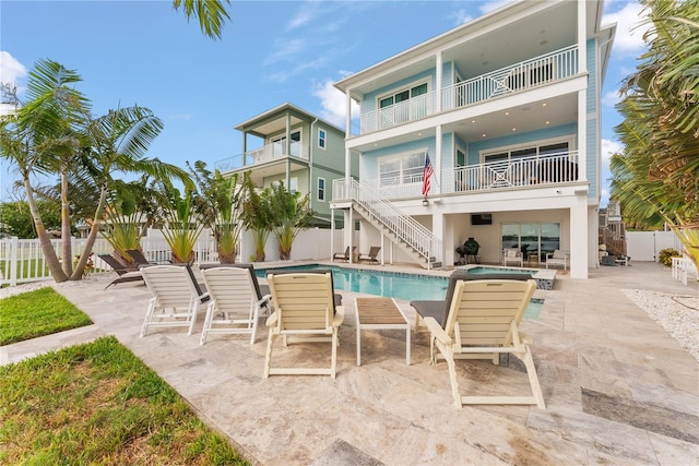 rear view of property featuring a balcony, a fenced backyard, stairs, and a patio area