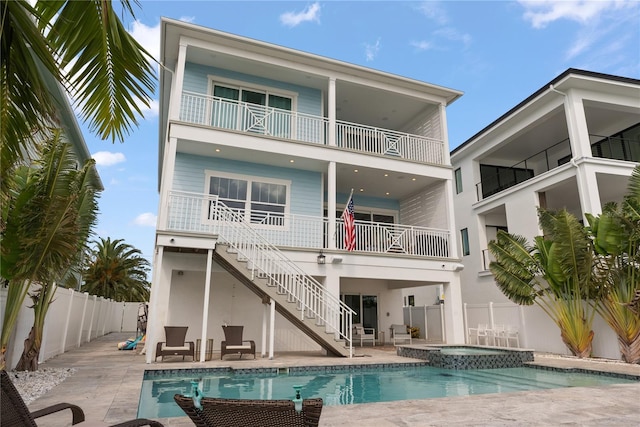 back of house featuring a balcony, stairway, a fenced backyard, a patio area, and a pool with connected hot tub