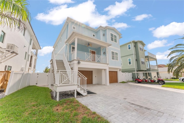 view of front of property featuring an attached garage, stairs, decorative driveway, a ceiling fan, and covered porch