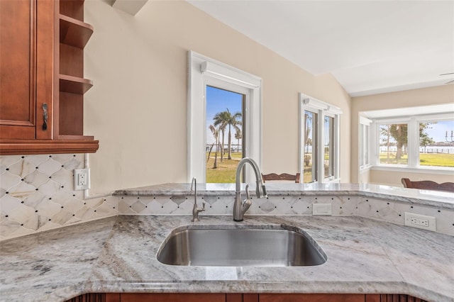 308 Chauncey Ave, Bradenton, FL 34208 - kitchen featuring a sink, open shelves, brown cabinetry, backsplash, and light stone counters