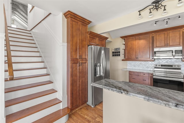 308 Chauncey Ave, Bradenton, FL 34208 - kitchen with light wood-style flooring, brown cabinetry, light stone counters, tasteful backsplash, and appliances with stainless steel finishes