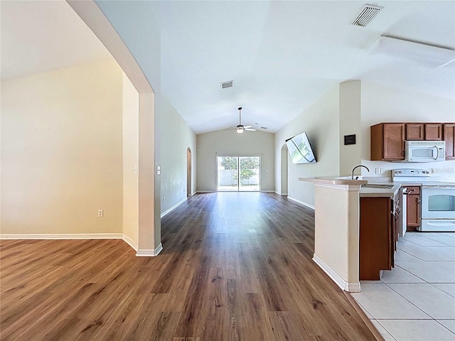 7504 Turtle View Dr, Ruskin, FL 33573 - kitchen featuring white appliances, open floor plan, lofted ceiling, arched walkways, and ceiling fan