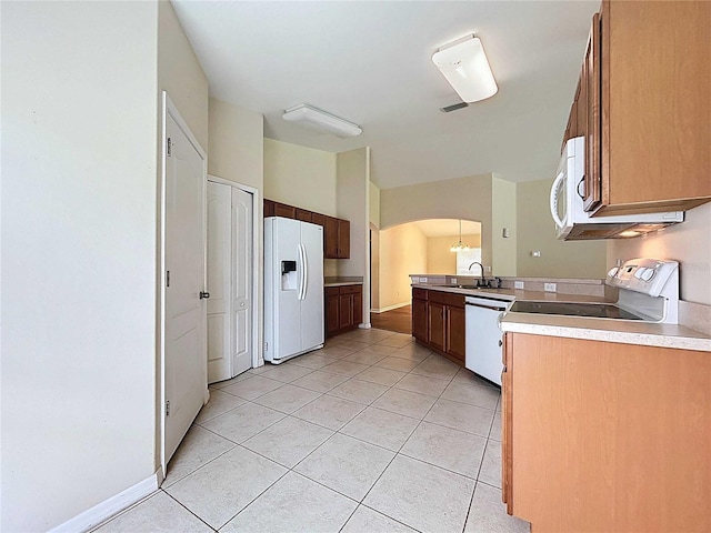 7504 Turtle View Dr, Ruskin, FL 33573 - kitchen featuring white appliances, arched walkways, light tile patterned floors, light countertops, and a peninsula
