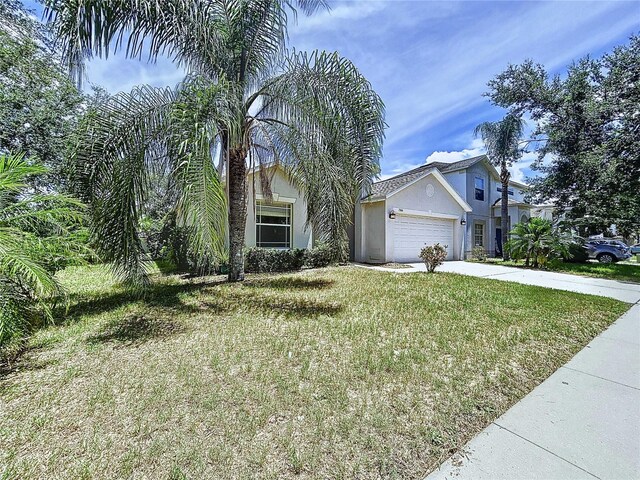 7504 Turtle View Dr, Ruskin, FL 33573 - view of property hidden behind natural elements with stucco siding, a front lawn, concrete driveway, and an attached garage