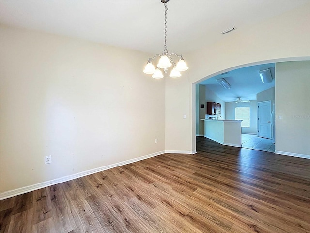 7504 Turtle View Dr, Ruskin, FL 33573 - empty room with wood finished floors, a chandelier, arched walkways, and ceiling fan