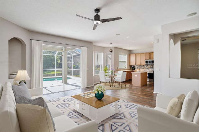 5804 Butterfield St, Riverview, FL 33578 - living area featuring ceiling fan, dark wood finished floors, baseboards, a textured ceiling, and arched walkways