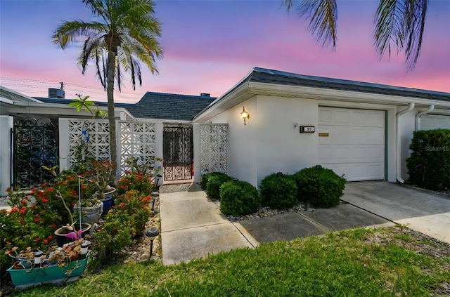 ranch-style house with stucco siding, an attached garage, a gate, concrete driveway, and fence