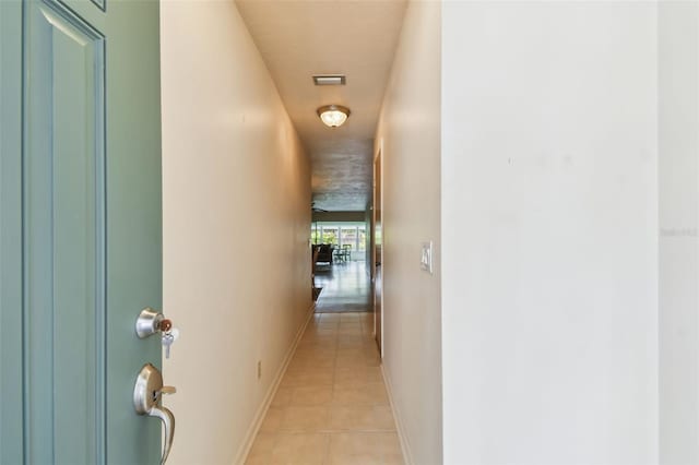 corridor with light tile patterned flooring and baseboards