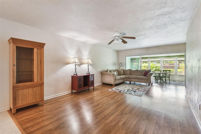 living room featuring a ceiling fan, wood finished floors, and baseboards