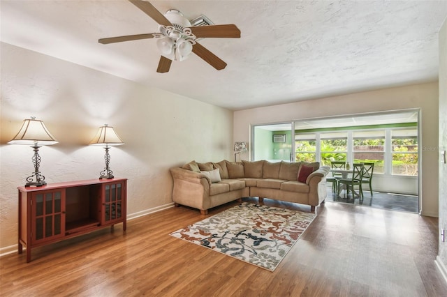 living room with wood finished floors, baseboards, and ceiling fan