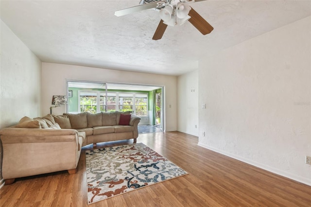 living area with wood finished floors, a ceiling fan, and baseboards