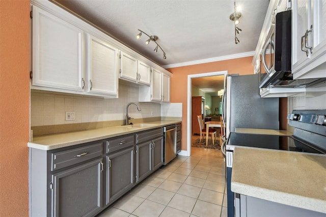 kitchen featuring appliances with stainless steel finishes, light tile patterned floors, ornamental molding, a sink, and gray cabinets