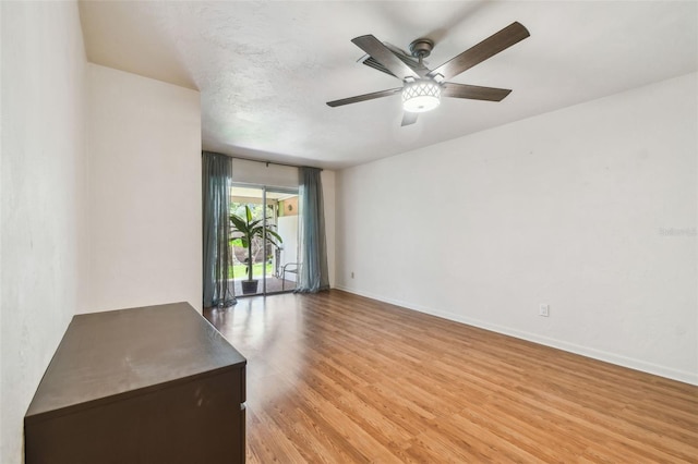 empty room with light wood-style flooring, a ceiling fan, and baseboards