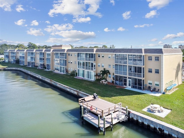 dock with a water view, a balcony, and a yard