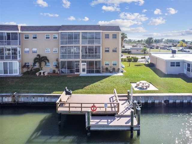 dock with a water view, a yard, and an outdoor fire pit