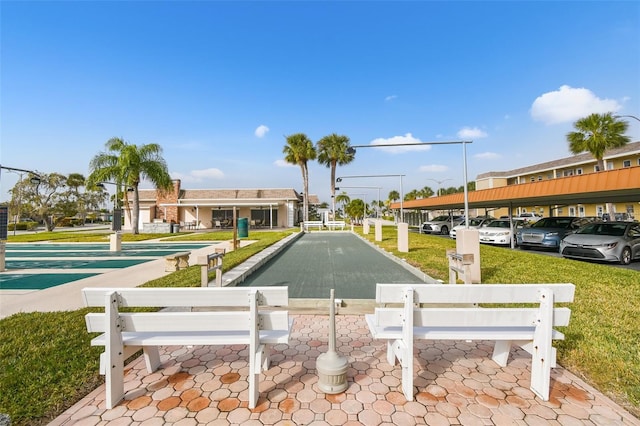 view of property's community featuring a bocce ball area and a parking lot