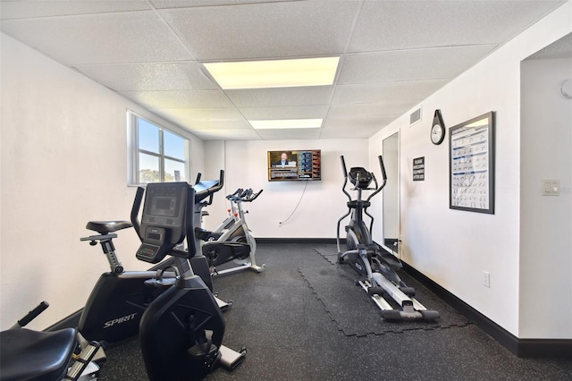 workout room with a paneled ceiling and baseboards